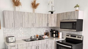 Una cocina moderna con armarios grises, una estufa negra, un microondas y un tostador.