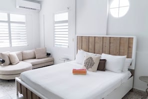 A bedroom with a bed, a sofa, a round table, and a window with blinds.