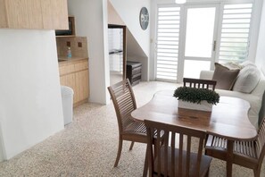 A compact living space with a dining area, a sofa, and a kitchen area.