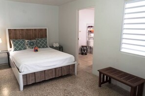 A bedroom with a bed, a bedside table, a bench, and a wardrobe.