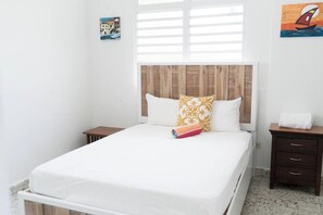 A single bed with a wooden headboard, two bedside tables, and a small nightstand.