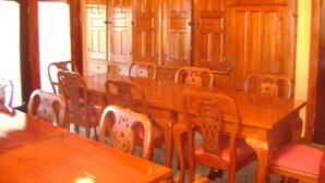 Une salle à manger avec une table et des chaises en bois, un ventilateur de plafond et des armoires en bois.