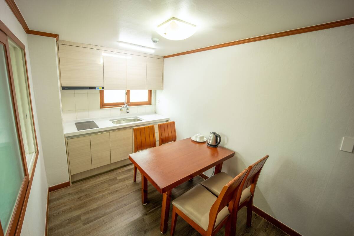 A compact kitchen with a wooden table and chairs, a window, and a built-in oven.