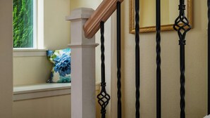 A staircase with a white column and black balusters. - Modern Updated Home, Game Room, Open Layout, Family Friendly, Near Intel & Nike 5 Min Walk to MAX (Beaverton)
