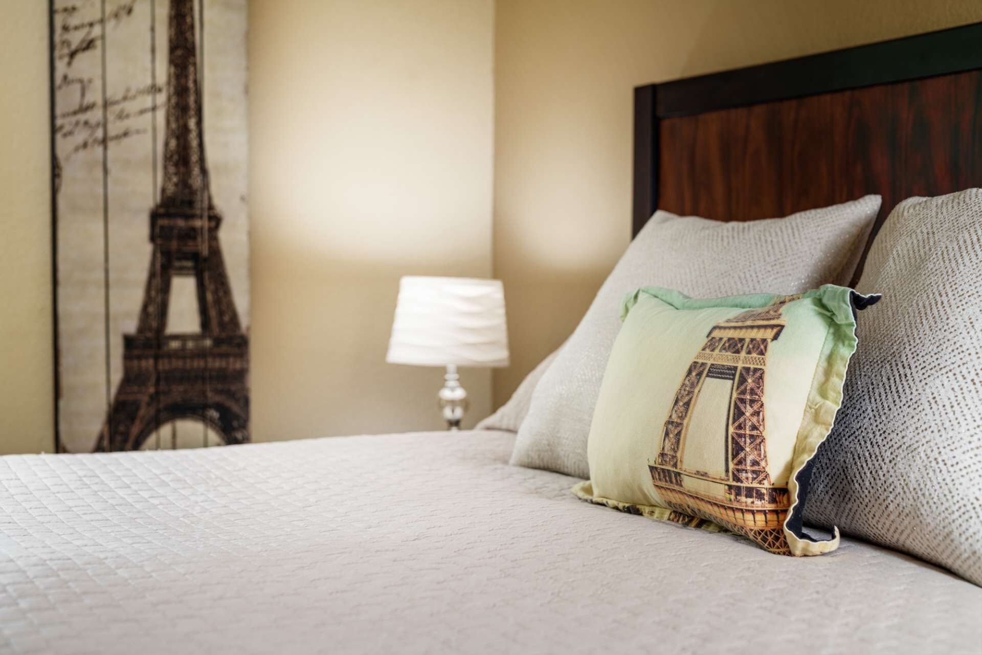 Ein Bett mit gesteppter Bettdecke, ein Kissen mit Muster und eine Lampe in einem Hotelzimmer.