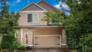 A two-story house with a garage, a front door, and a small porch. - Modern Updated Home, Game Room, Open Layout, Family Friendly, Near Intel & Nike 5 Min Walk to MAX (Beaverton)