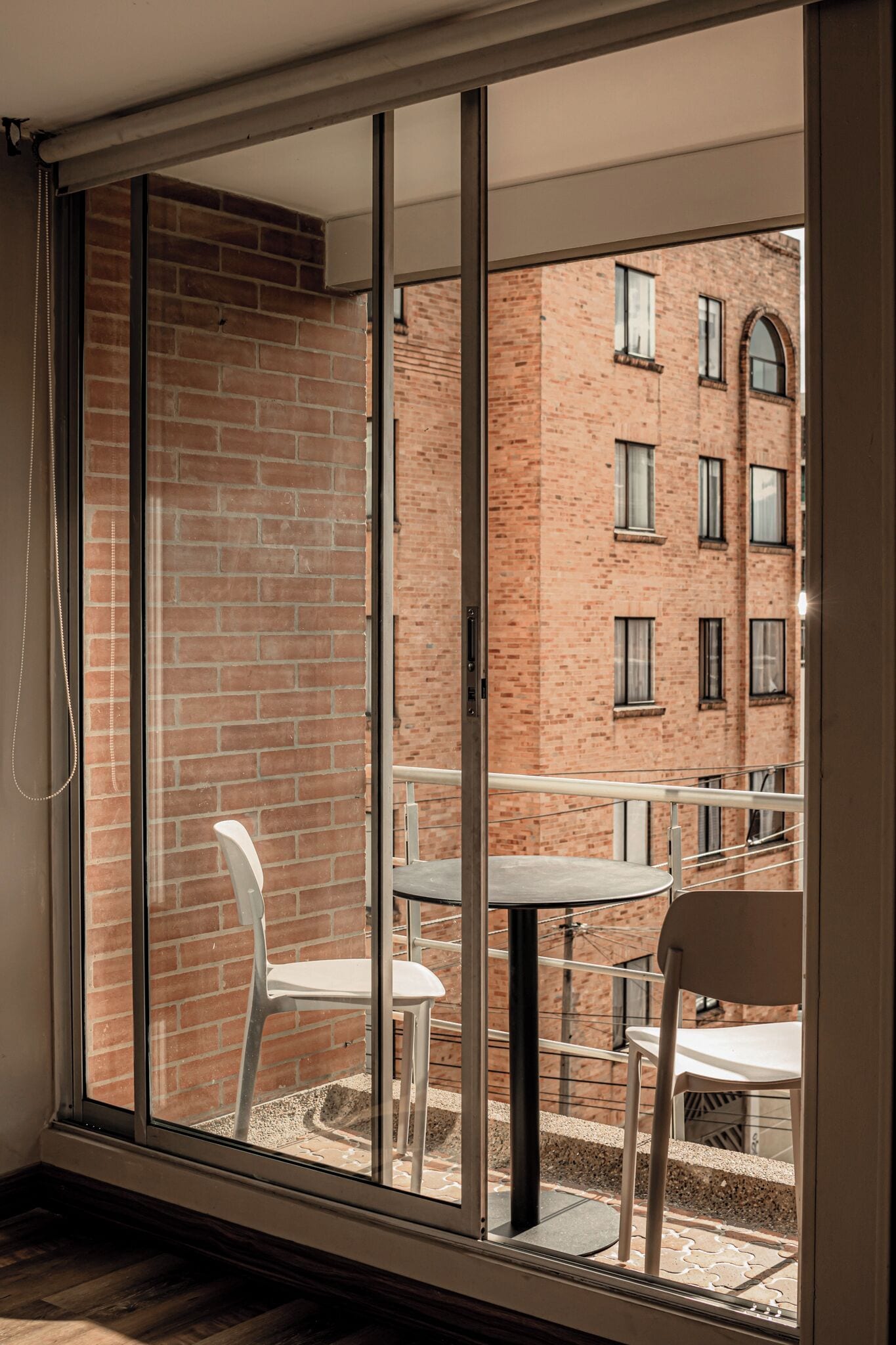 A room with a sliding glass door leading to an outdoor balcony with a brick building in the background.