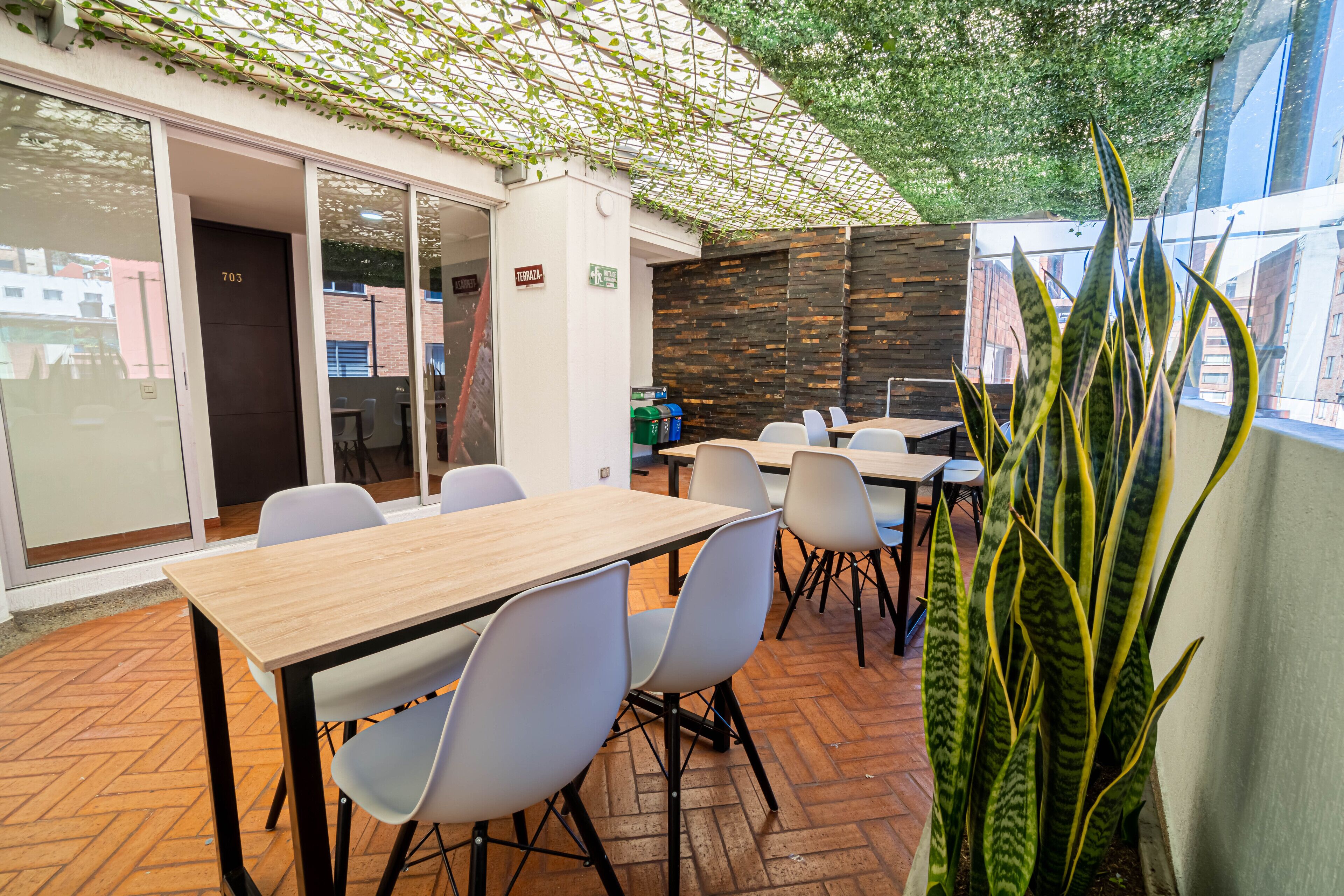 Un espace de restauration intérieur avec des tables et des chaises, un sol en briques et une plante.