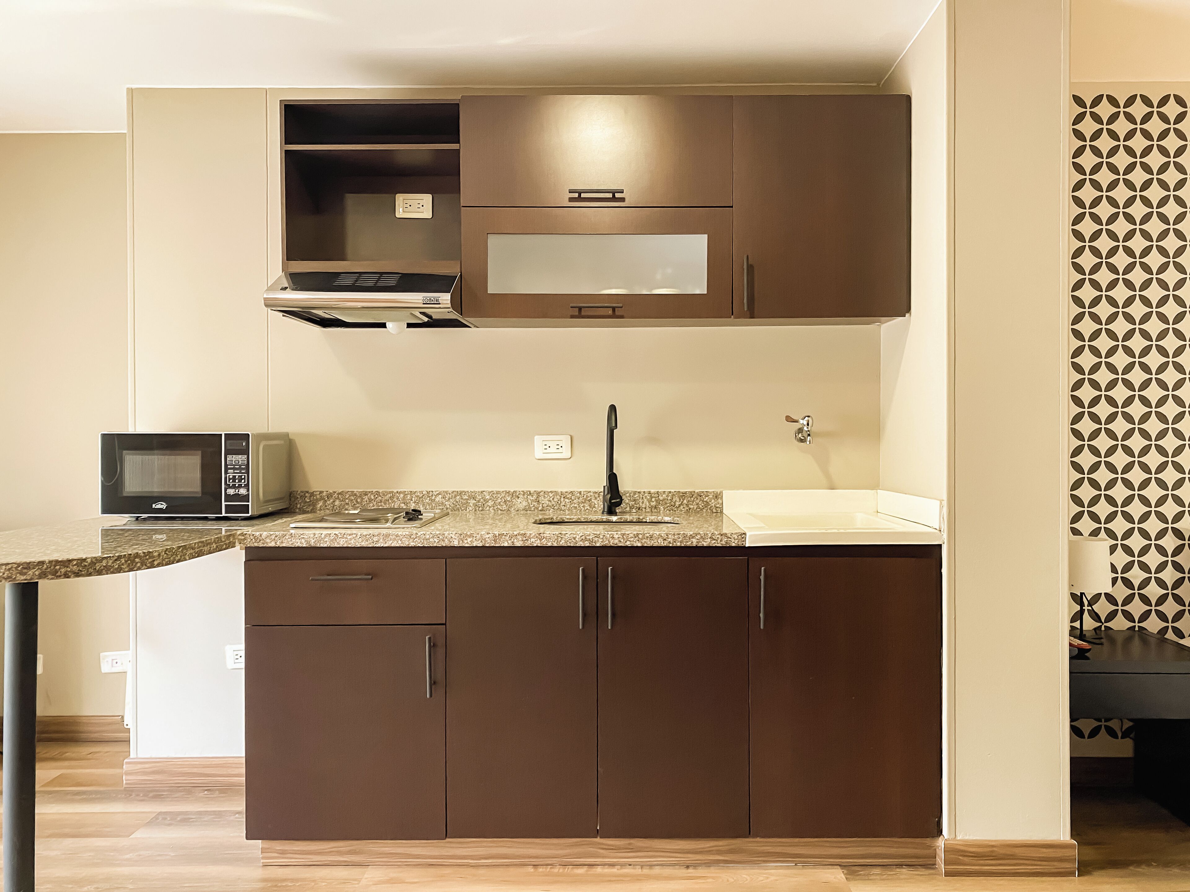 A compact kitchen with a microwave, sink, and cabinets.