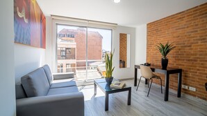 A modern living room with a sofa, a coffee table, a dining table, and a potted plant. - Hemma Bogotá Chapinero Premium Suites Hotel (Bogotá)