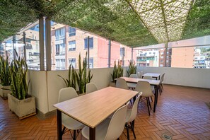 An outdoor patio with tables and chairs, surrounded by potted plants and a view of buildings. - Hemma Bogotá Chapinero Premium Suites Hotel (Bogotá)