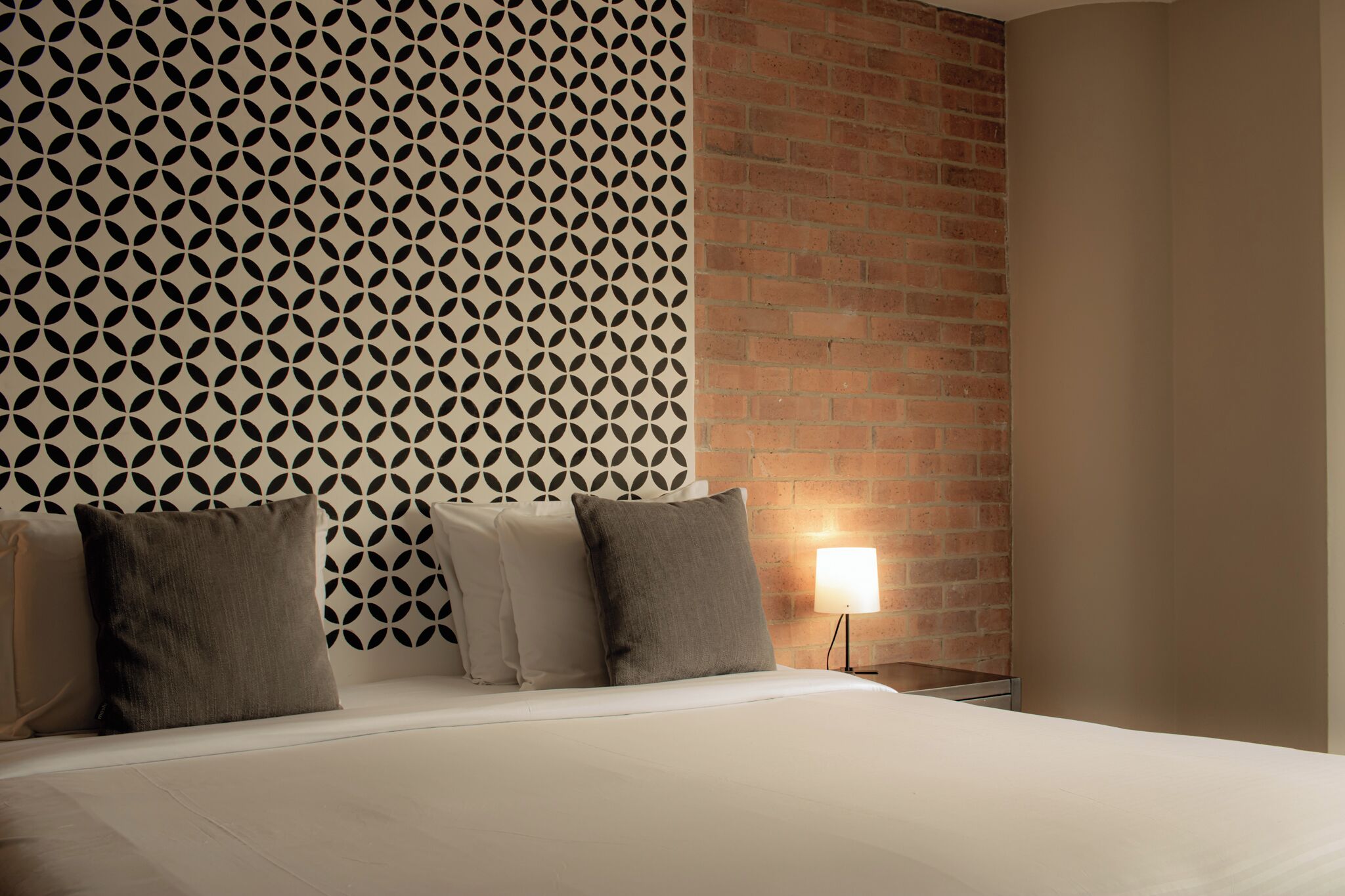Ein Hotelzimmer mit Wandverkleidung, einer Ziegelauslage und einer Nachttischlampe.