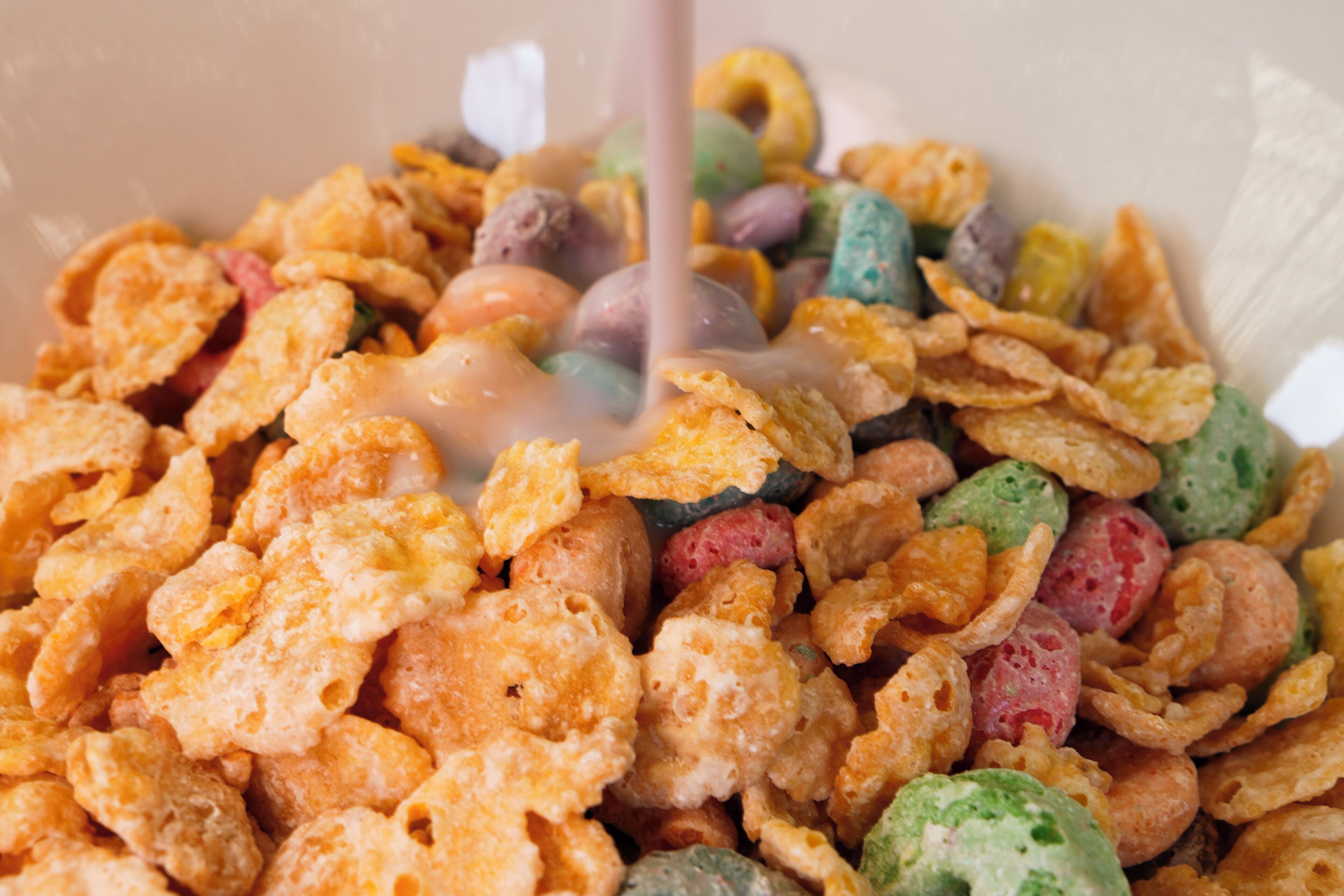 A bowl of cereal with milk being poured.