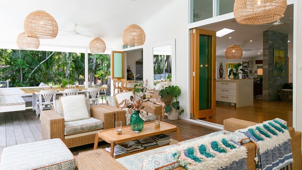 A spacious living area with wicker furniture, a coffee table, and hanging rattan lamps.