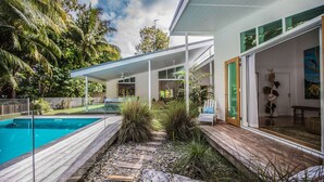 A modern house with a swimming pool, covered outdoor seating area, and a large glass door leading to a patio.