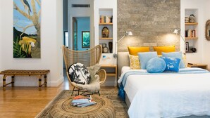 A bedroom with a bed, bedside tables, a chair, a bench, and a bookshelf.