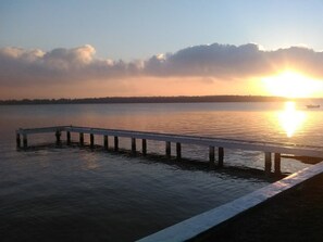 A pier extending into calm water during sunset.