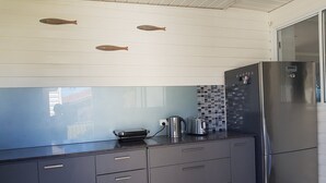 Eine moderne Küche mit grauen Schränken, einem Edelstahlkühlschrank und einer gefliesten Spritzschutzwand.
