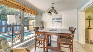 Un comedor con una gran mesa de madera, seis sillas y vistas a una piscina a través de amplios ventanales.