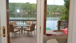 A deck with a table and chairs, overlooking a lake. - Lakeside cottage overhanging the water, beautiful window views across the lake (Ledyard)