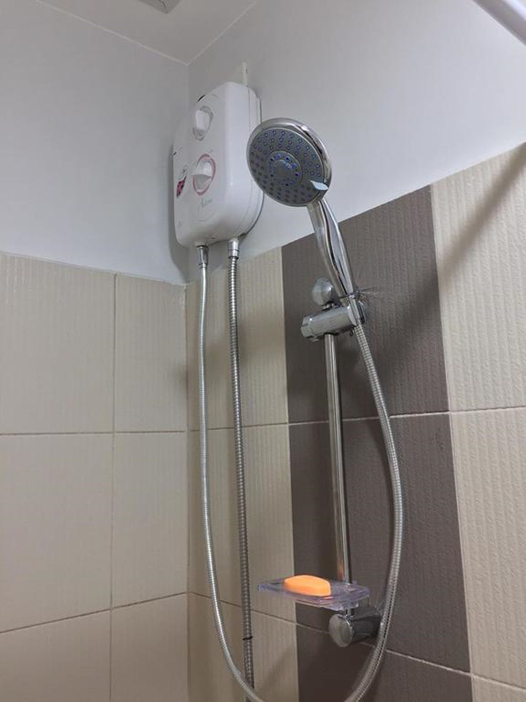 A shower with a handheld showerhead and a handheld water pump.