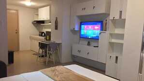 A compact bedroom with a bed, a desk, and a television. - M Place at Abs by Noemi (Quezon City)