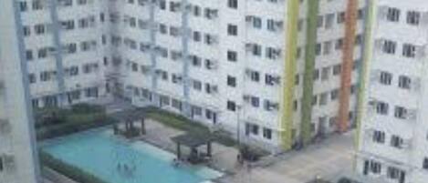A high-rise building with multiple swimming pools and a central courtyard.