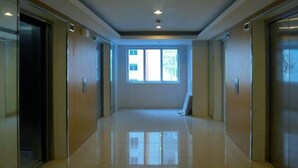 A hallway with a shiny floor, glass doors, and a window at the end. - M Place at Abs by Noemi (Quezon City)