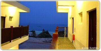 Un pasillo que da a un balcón con vista a una playa al atardecer.