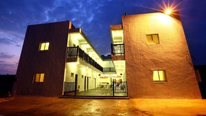 A modern building with a courtyard, featuring a covered outdoor seating area and multiple windows. - Xiang xie Homestay (Baisha)