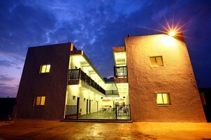 Un edificio moderno con patio central, que cuenta con un área de estar cubierta al aire libre y múltiples ventanas.
