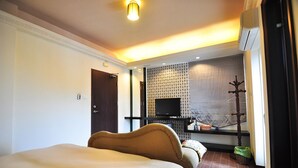 A hotel room with a bed, a television, a small table, and a window with blinds. - Xiang xie Homestay (Baisha)