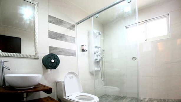 A modern bathroom with a glass-enclosed shower, a white toilet, and a wooden vanity with a sink.