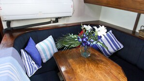 Uma cabana com mesa de madeira, assentos estofados em azul e um vaso com flores.