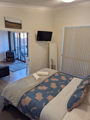 Un dormitorio con cama, televisión, chimenea y vistas al exterior.