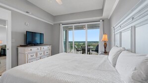 A bedroom with a large bed, a television, a dresser, and a balcony with a table and chairs. - Waterfront Condo | Marina Views | Pools & Lazy River | On-Site Dining | Sleeps 8 (Orange Beach)