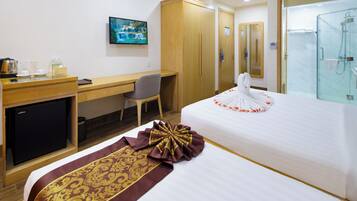 A hotel room with a bed, a desk, a chair, a television, and a shower area.