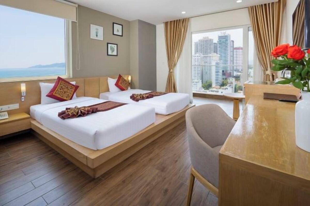Habitació d'hotel amb dos llits, un escriptori i vista a la ciutat.