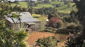 Escape to a serene countryside retreat surrounded by lush vegetation and rolling hills.
