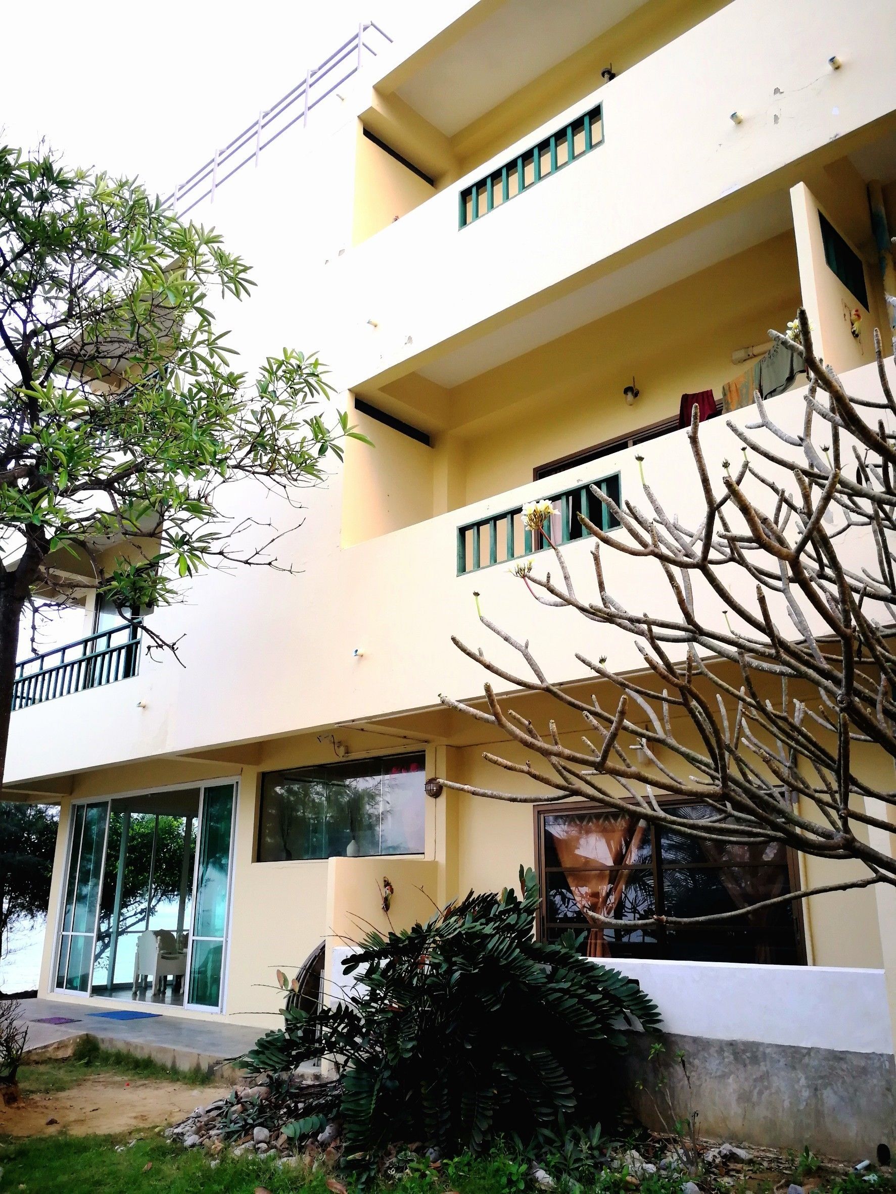 A multi-story building with balconies, large windows, and a garden area.