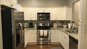 Una cocina moderna con armarios blancos, electrodomésticos de acero inoxidable y encimeras de granito.