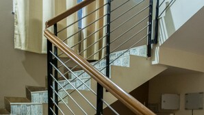 A staircase with patterned tiles and a wooden handrail. - 3BHK by Tripvillas Holiday Homes (Paud)