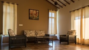 A spacious living room with a sofa, two armchairs, a coffee table, and a painting on the wall. - 3BHK by Tripvillas Holiday Homes (Paud)