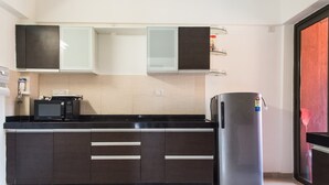 A modern kitchen with dark cabinets, a stainless steel refrigerator, and a microwave. - 3BHK by Tripvillas Holiday Homes (Paud)