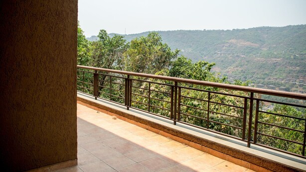 A balcony with a metal railing overlooking a hilly landscape.