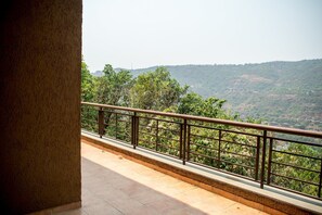 A balcony with a metal railing overlooking a hilly landscape.