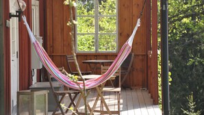 A wooden deck with a hammock, wooden chairs, and a table. - Grab your chance! Our plans have changed making Nickebo bookable after all! (Torsby)