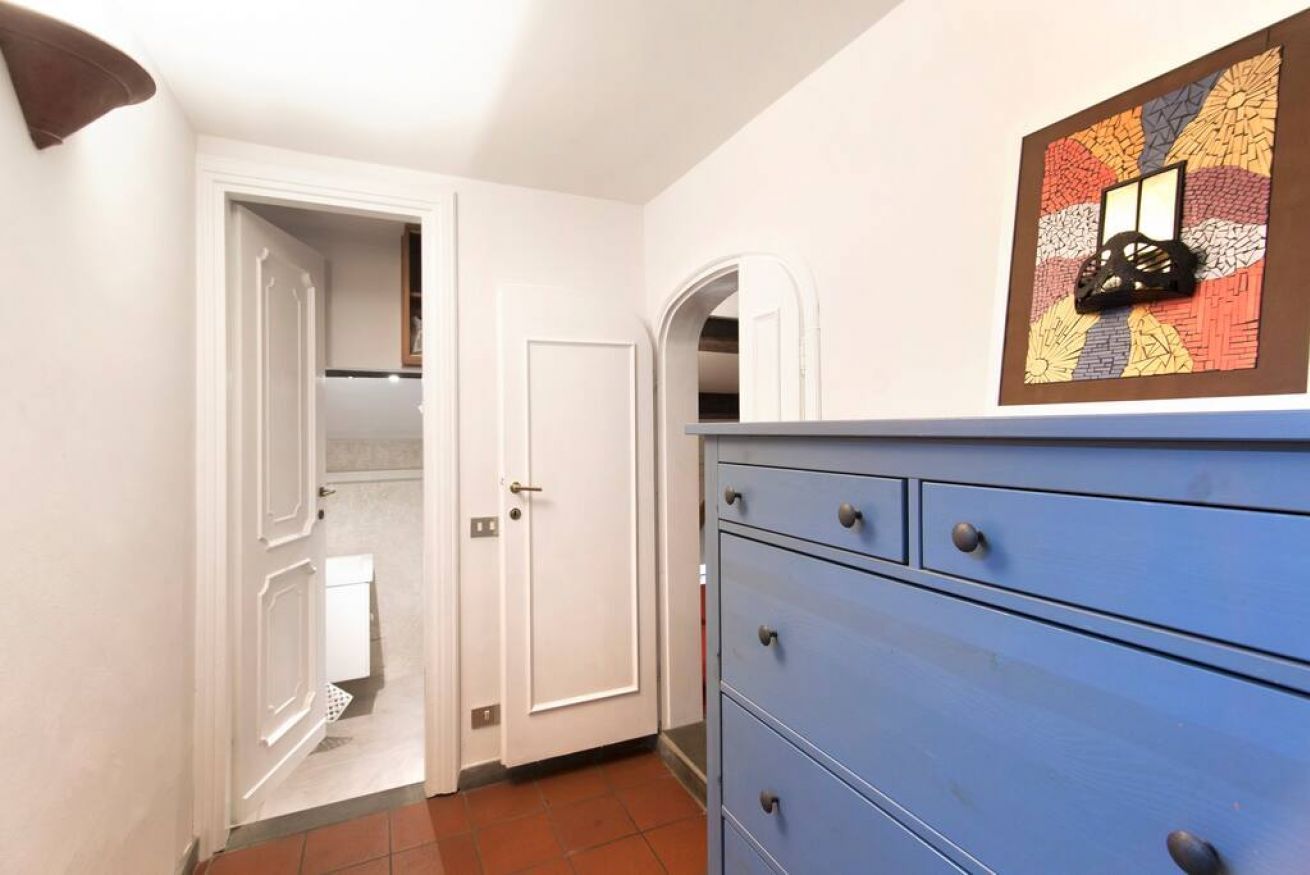 A hallway with a blue dresser, a white door, and a colorful artwork on the wall.