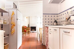 Una cocina con armarios blancos, un microondas y una tetera sobre la encimera.