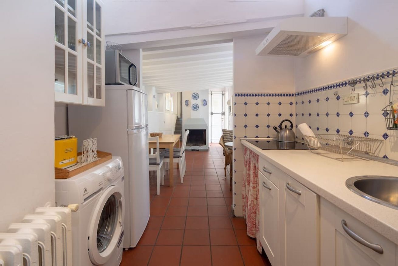 Een kleine keuken met een wasmachine, een magnetron en een spoelbak.